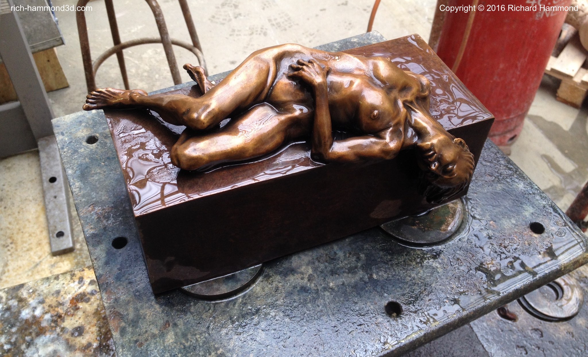 Here the patination is complete and water has been poured to allow it to be assessed before the final waxing and polishing.